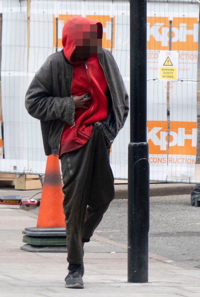 Person in red hoodie standing near a construction site.