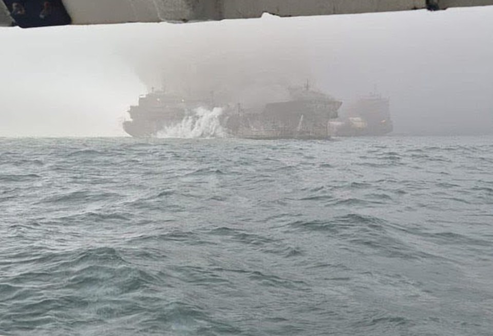 A burning oil tanker in rough seas.