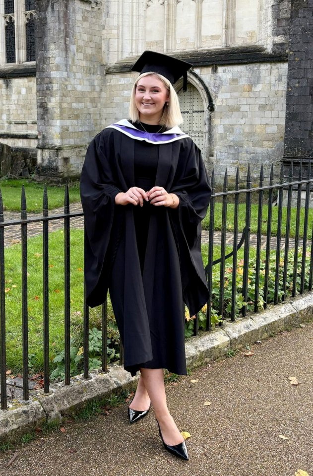 Graduate in cap and gown posing outdoors.