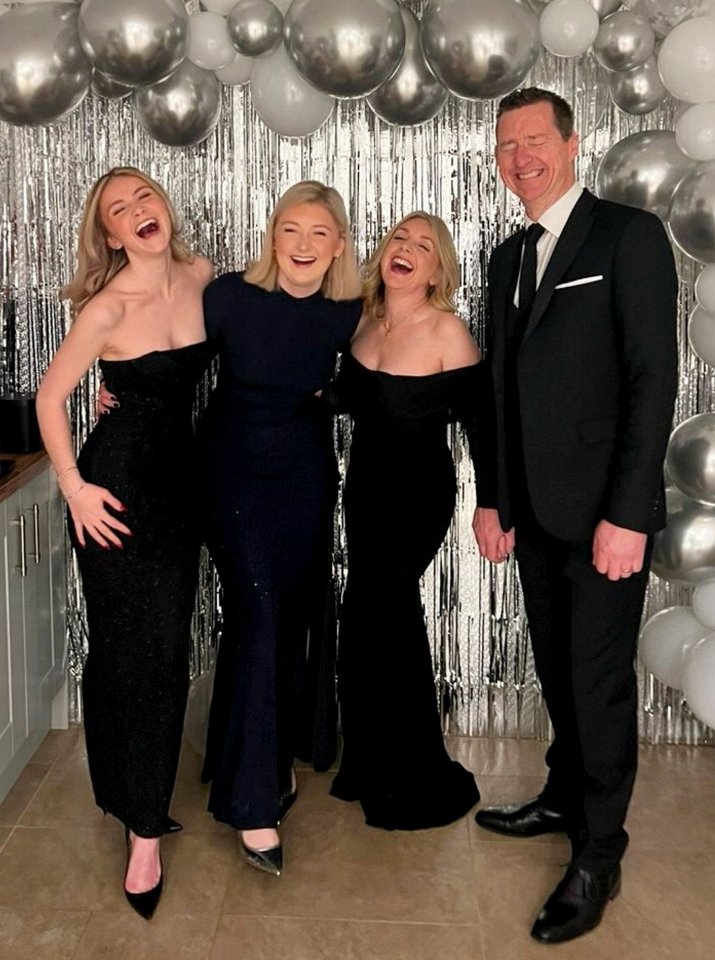 Family photo in front of a silver balloon backdrop.