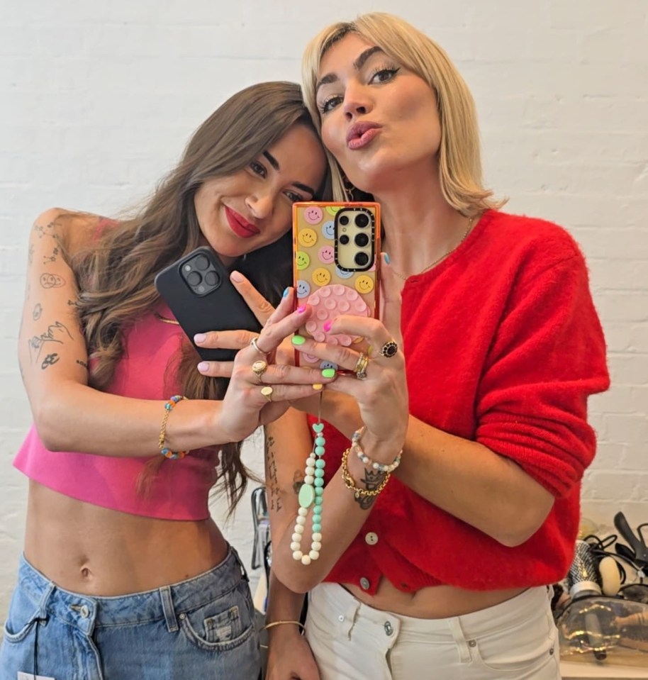 Two women taking a selfie with their phones.