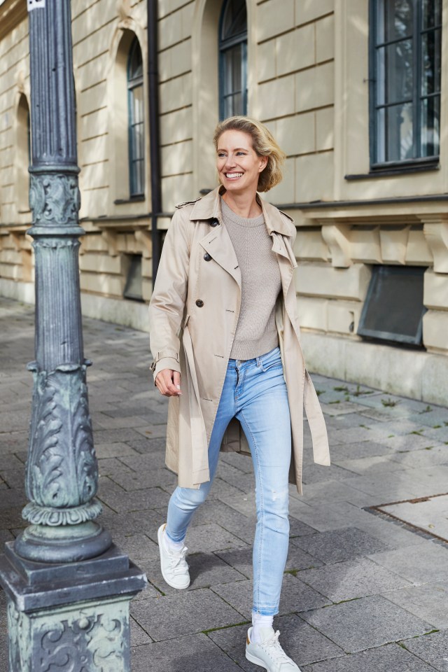 A smiling woman walking down a city street.
