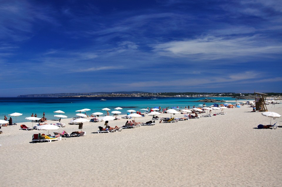 Beach scene with people relaxing under umbrellas.
