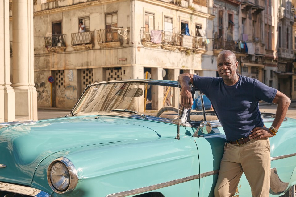 Man leaning on a teal classic car in Havana.