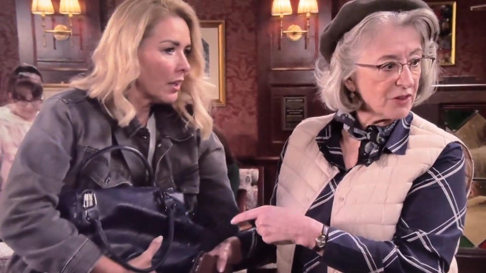 Two women in a pub, one holding a handbag, the other pointing.