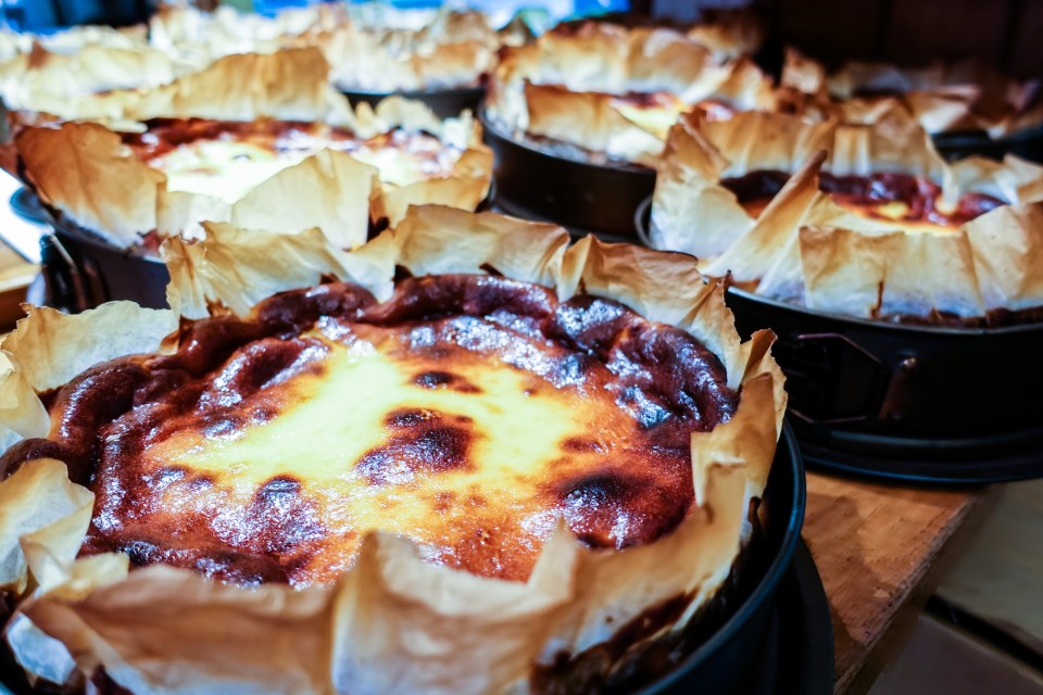 Several baked cheesecakes in individual pans.