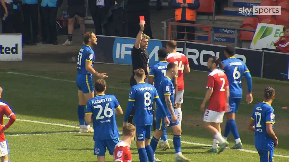 A soccer referee showing a red card to a player.
