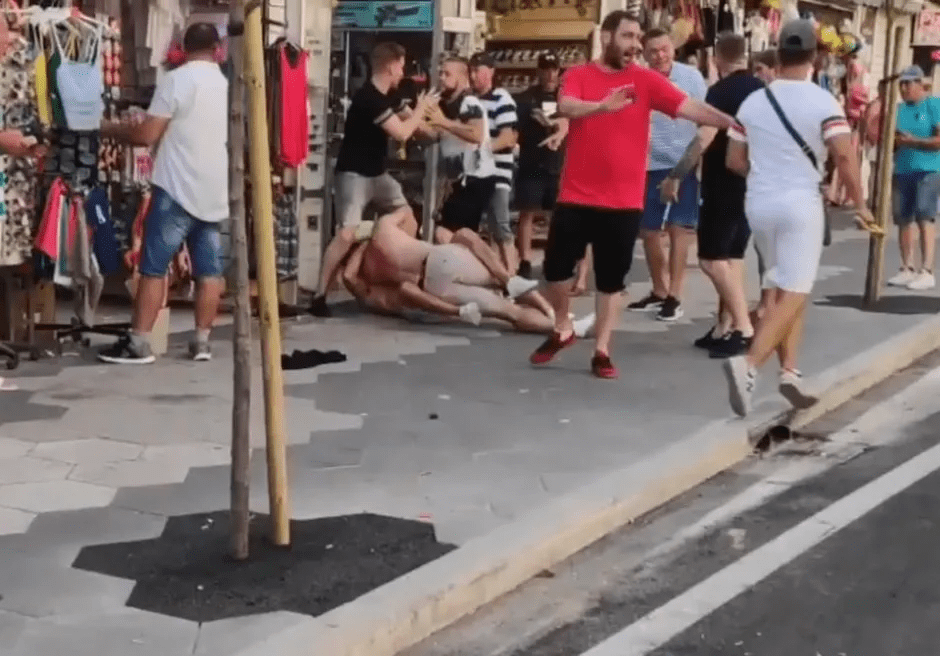 A man being beaten on a Benidorm street by several men.