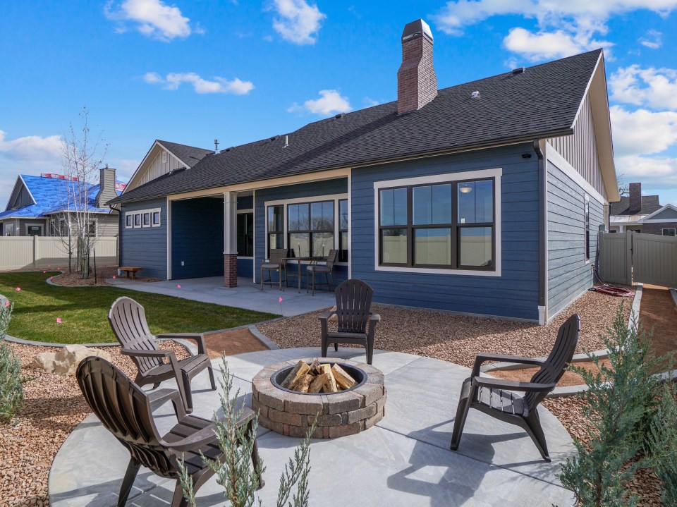 Modern home with landscaped backyard featuring a fire pit and patio furniture.