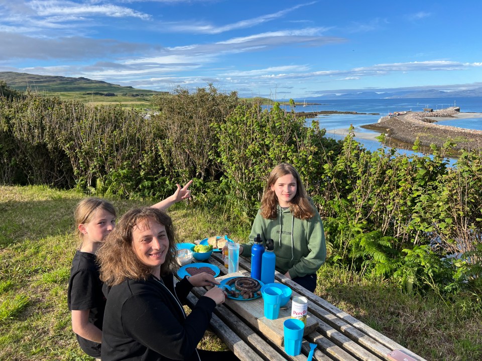Family enjoying a meal outdoors overlooking the coast.