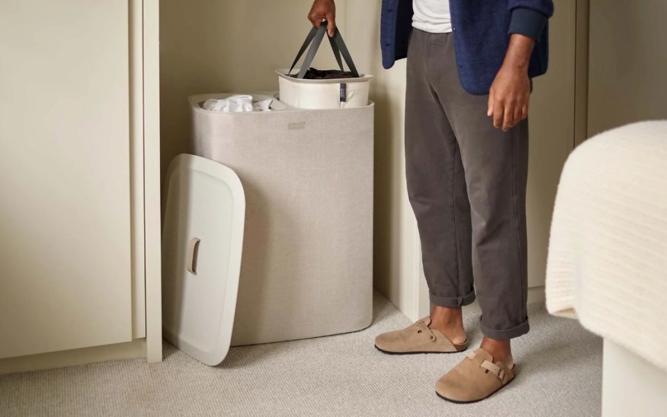 Person placing laundry basket into a larger laundry separation basket.