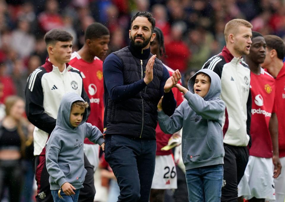Ruben Amorim, manager of Manchester United, applauds fans with two young boys.
