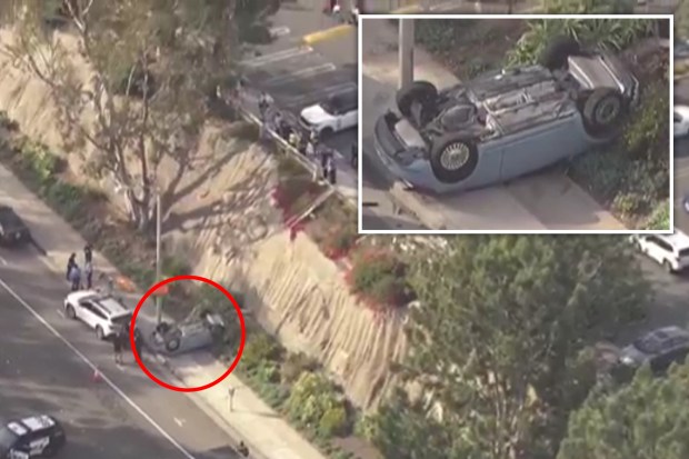 Aerial view of an overturned car on the side of a road with emergency personnel on scene.