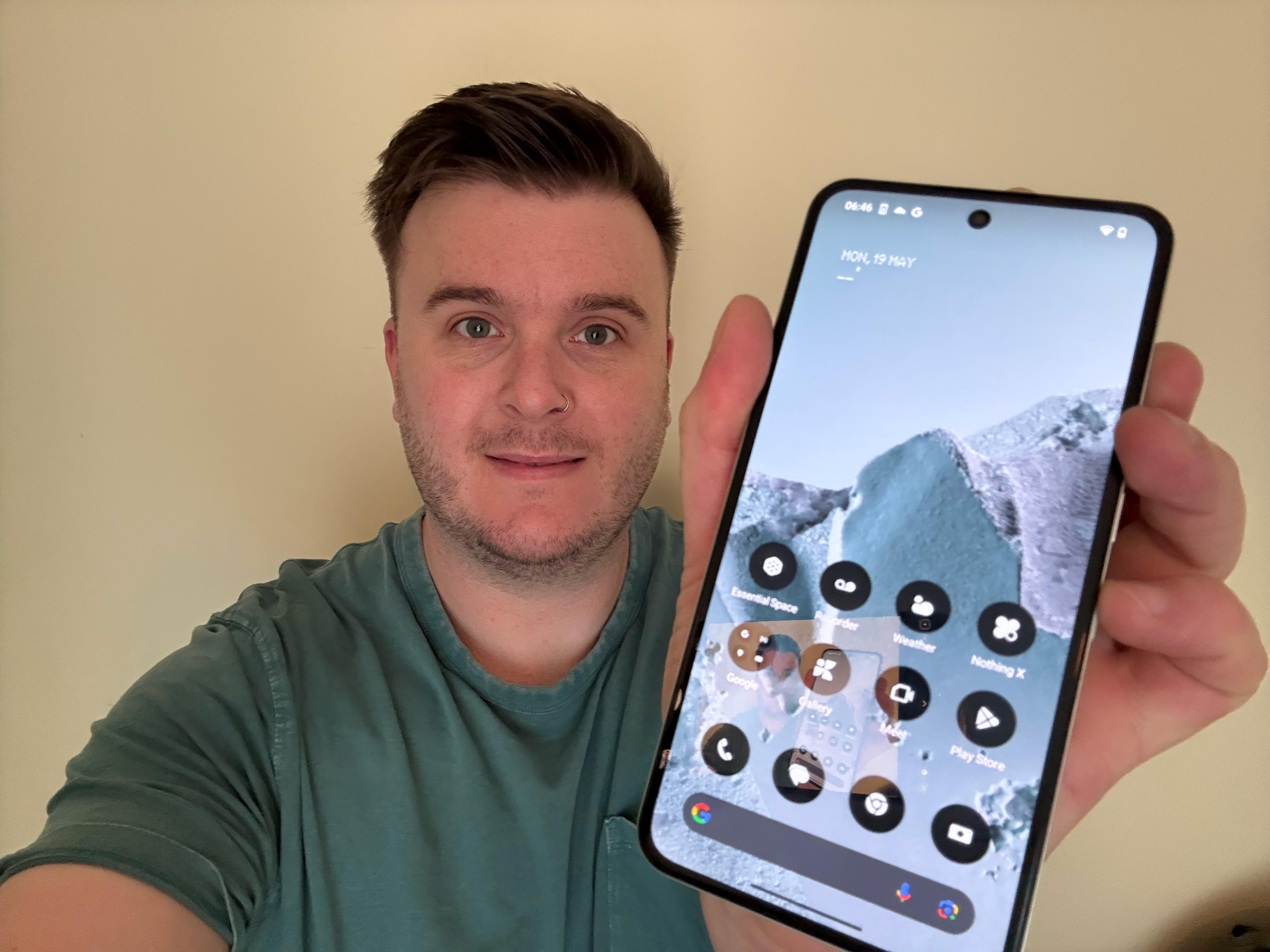 Person holding up a smartphone displaying its home screen.