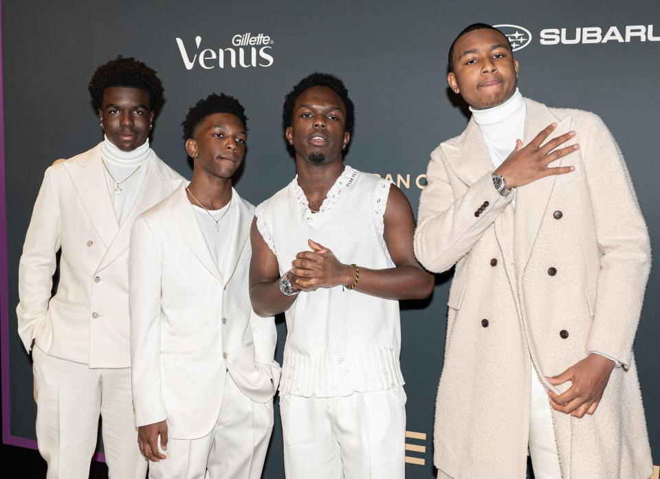 Four young men in white suits at an awards ceremony.