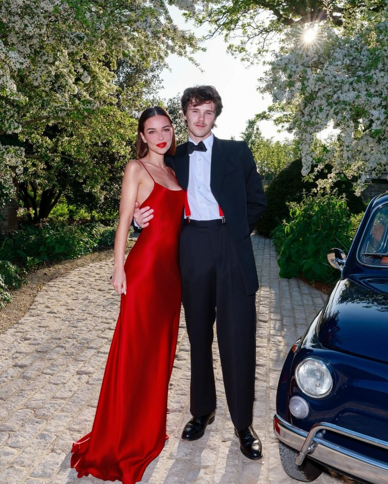 Couple in formal wear posing outdoors.