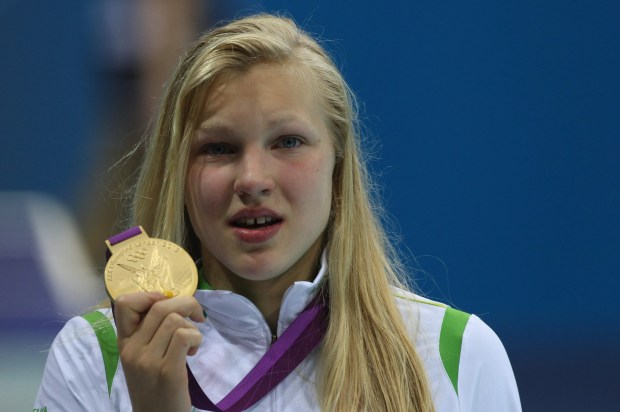 A teenage girl, gold medalist, displays her medal.