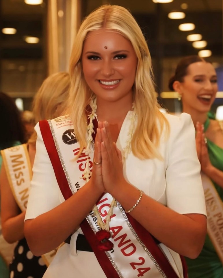Miss England, Milla Magee, in a white dress and sash, performing a traditional greeting.