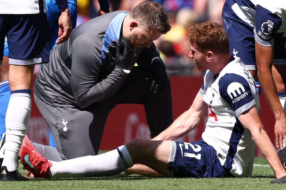 Dejan Kulusevski of Tottenham Hotspur receiving medical attention on the field.