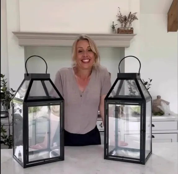 Woman standing between two large black lanterns.