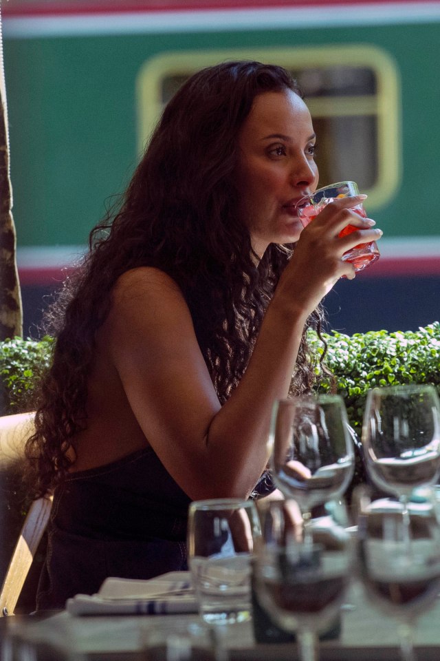 Maya Jama drinking a cocktail at an outdoor restaurant.