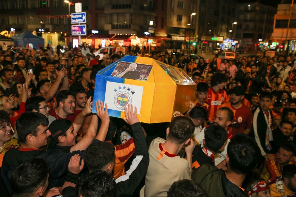 Galatasaray fans celebrating their team's championship title, carrying a decorated box.