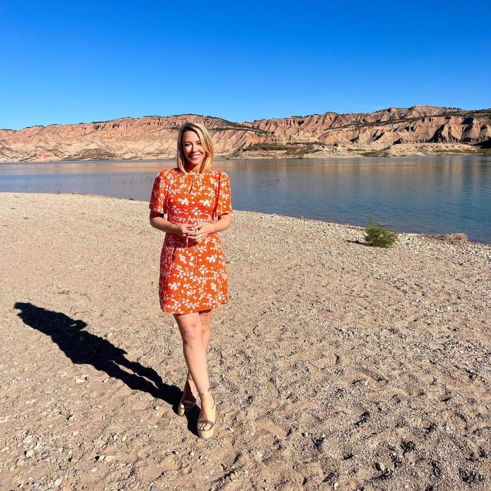 Laura Hamilton in an orange floral dress by a lake.