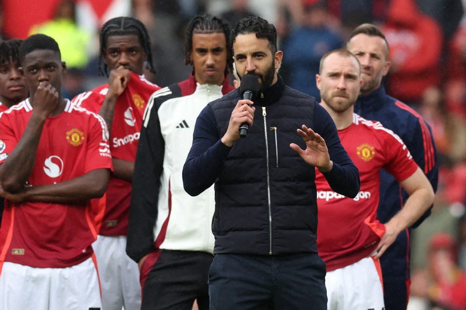 Manchester United's head coach speaking into a microphone with players behind him.