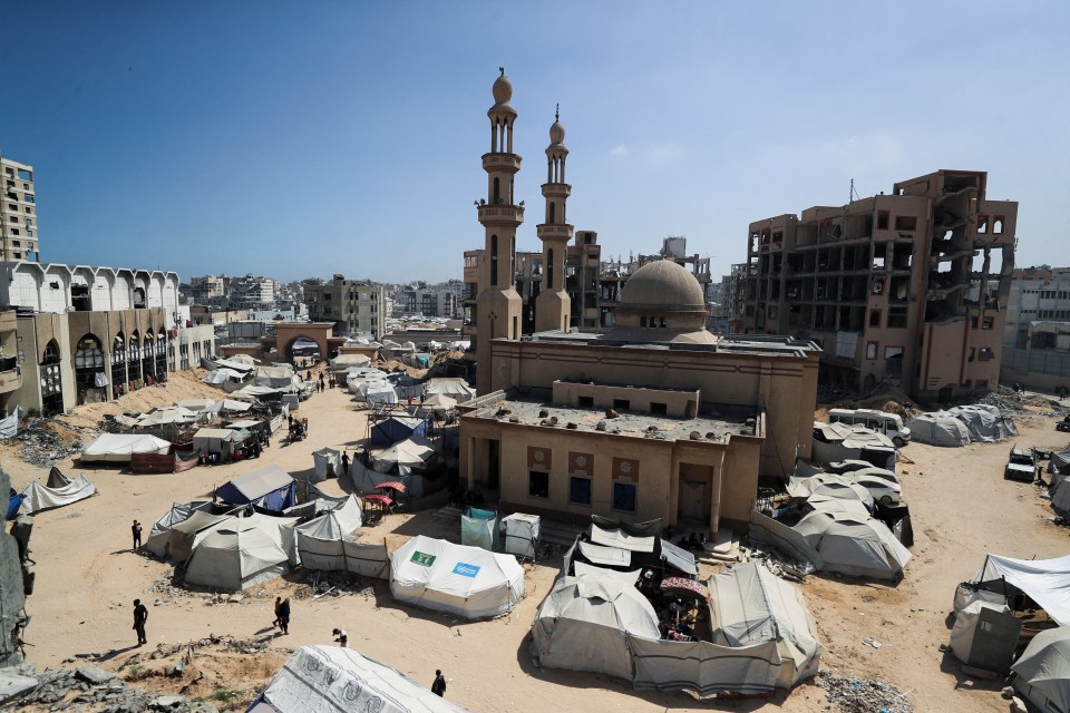 Displaced Palestinians in Gaza City sheltering in tents amidst damaged buildings.