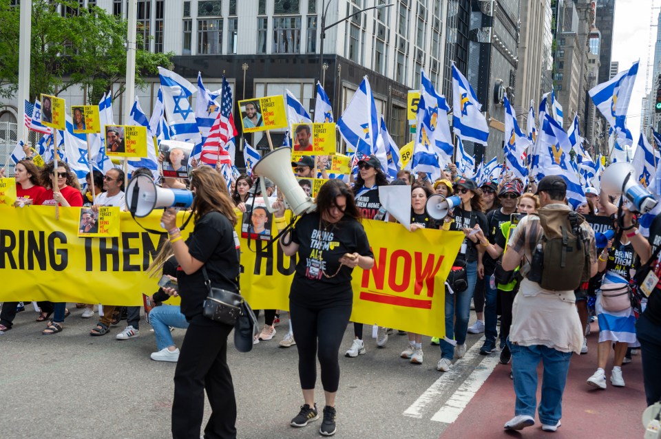 Marchers at the Israel Day Parade carry signs demanding the release of hostages.