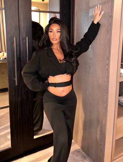 Pregnant Chelsee Healey in a black cropped blazer and pants.