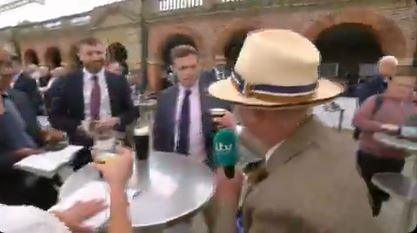 Man in hat drinking Guinness with others.