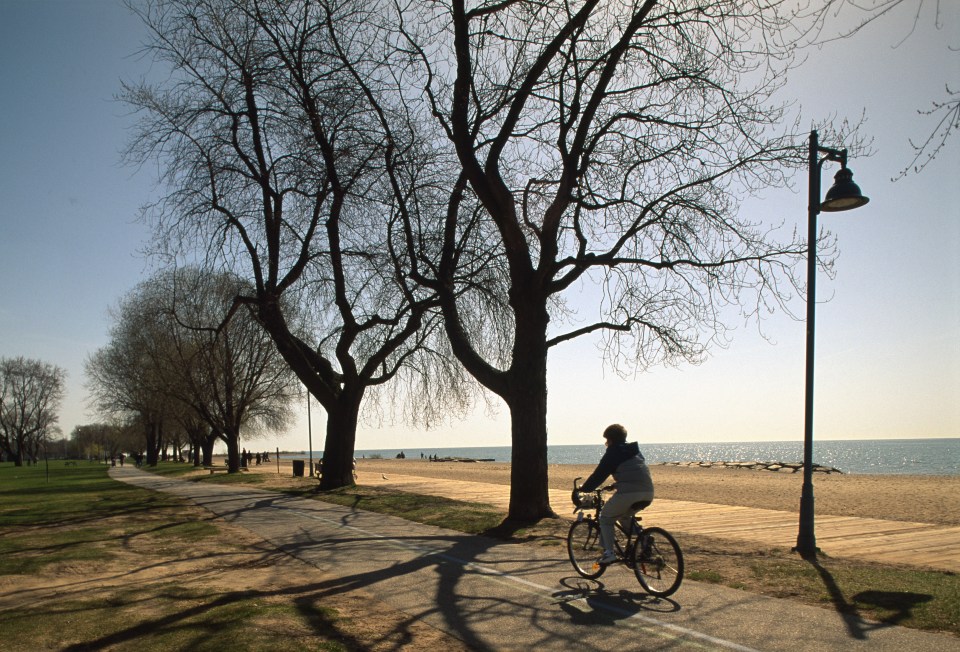 Woman cycling along a beach path.