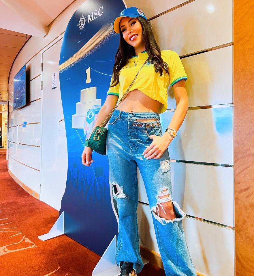 Woman in yellow shirt and ripped jeans posing by a number one sign.