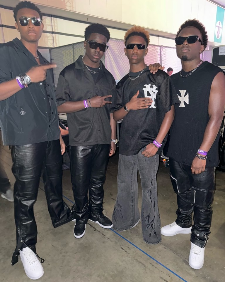 Four young men in black clothing and sunglasses.