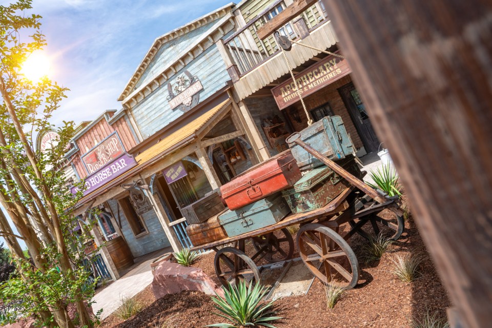 A luggage cart sits in front of Wild West-themed buildings at Europa-Park.