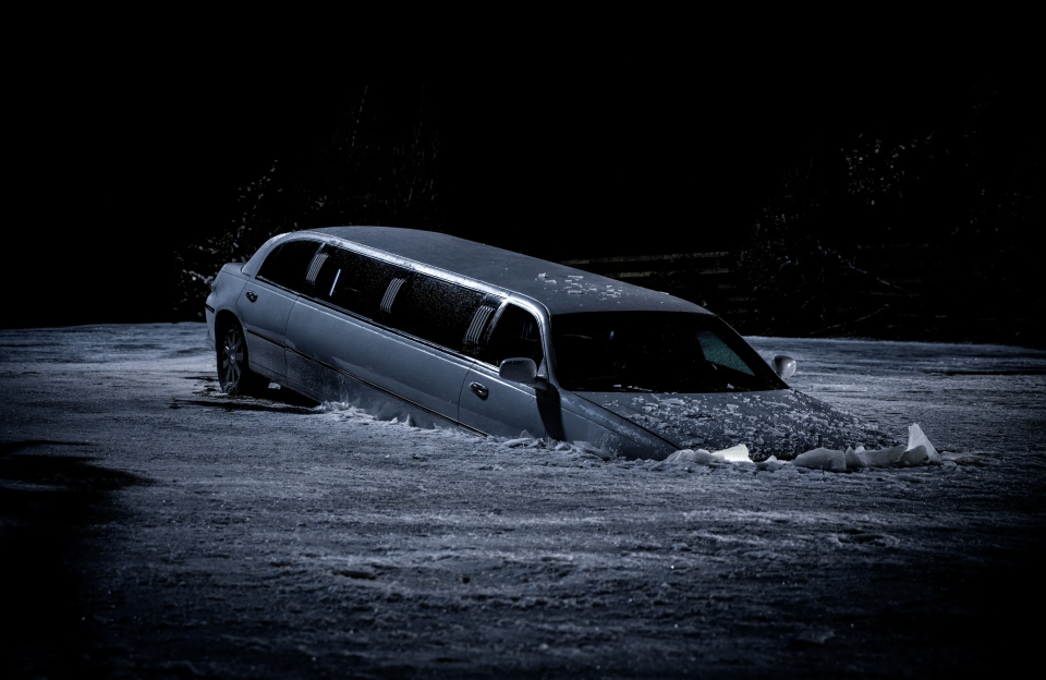 Limousine partially submerged in snow at night.