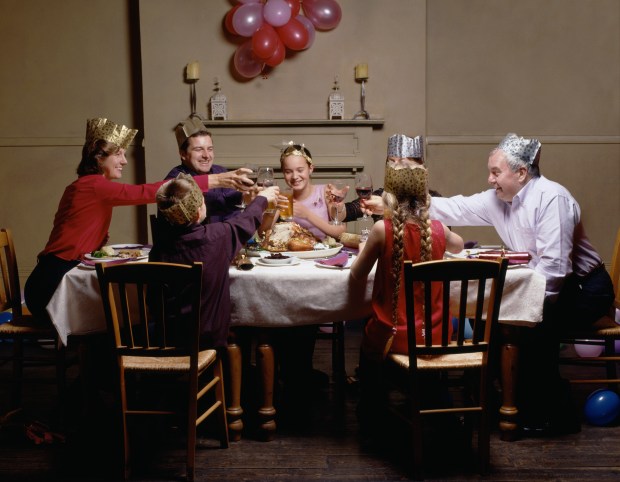 Family toasting drinks sitting at christmas dinner table
