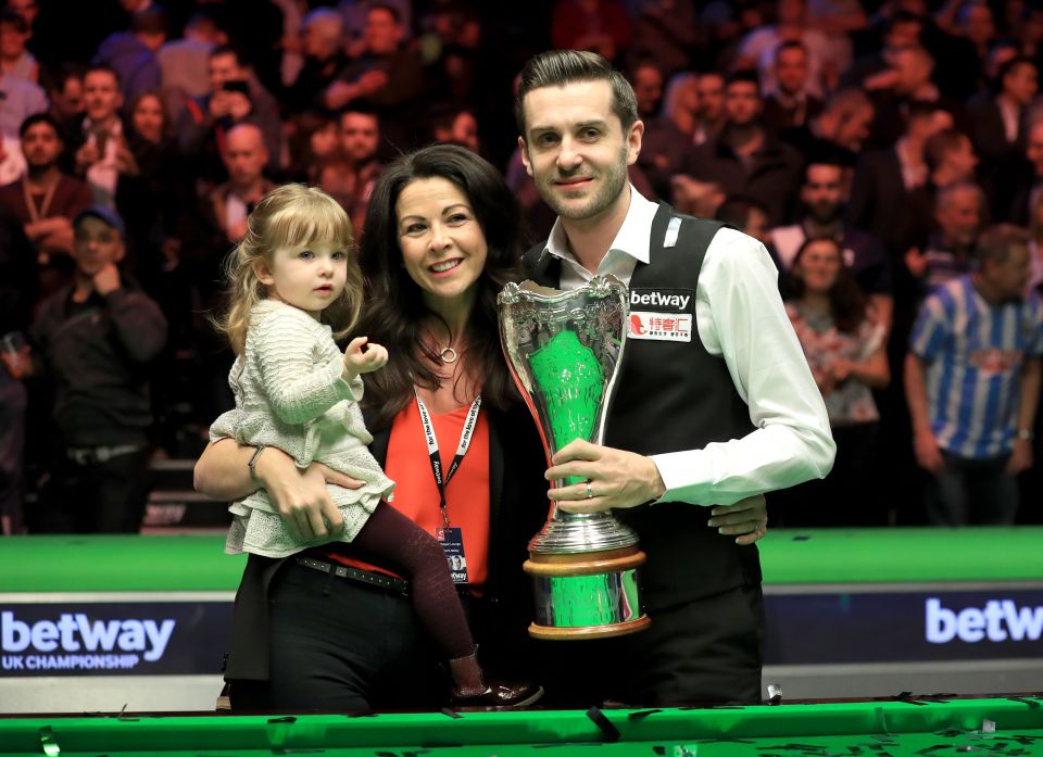 Snooker player Mark Selby celebrates a championship win with his wife and daughter.