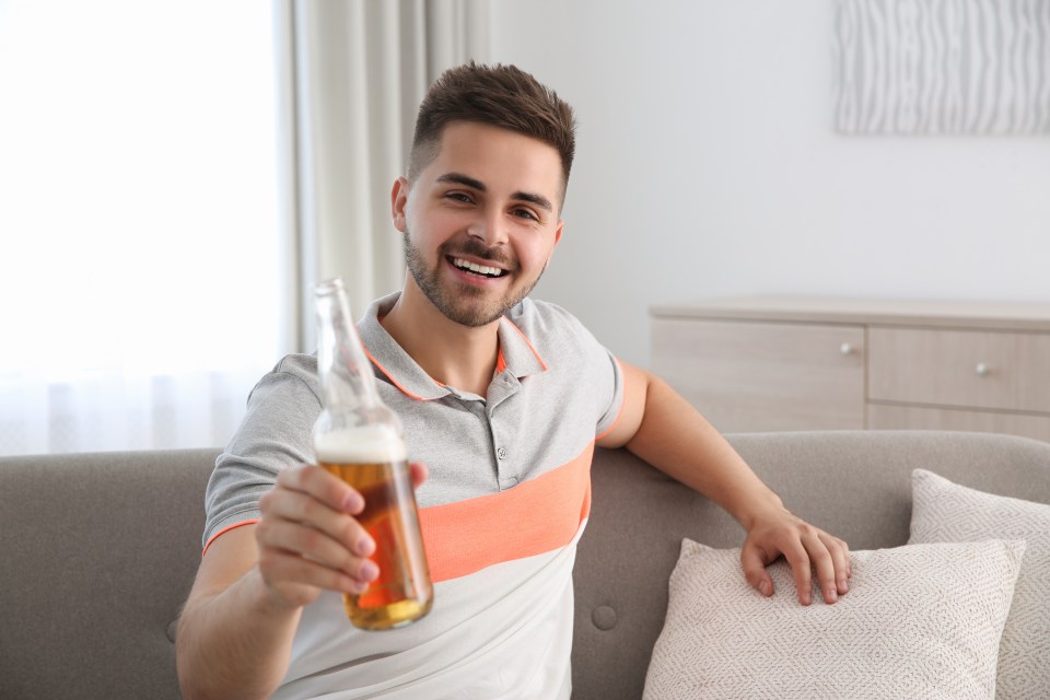 a man sitting on a couch holding a bottle of beer