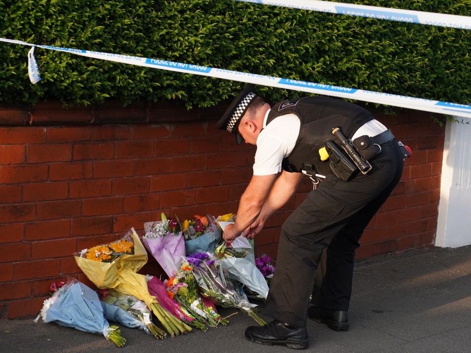 a police officer is putting flowers in front of a brick wall