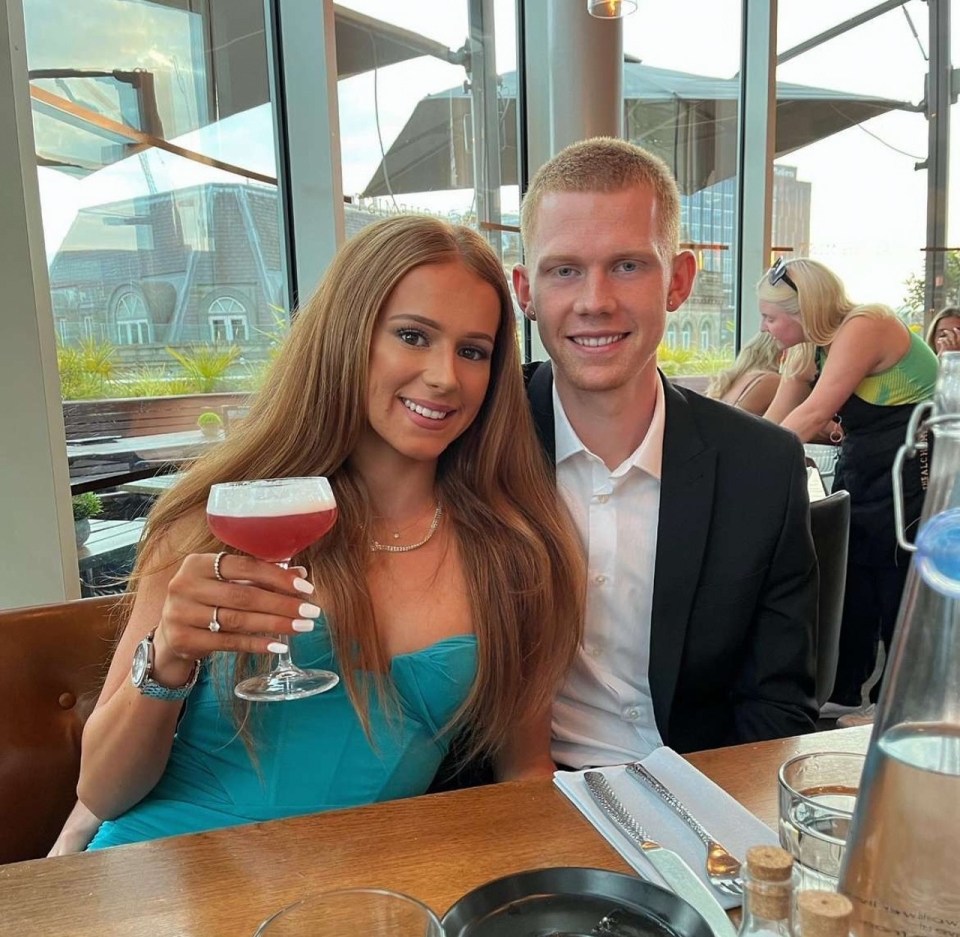 a man and a woman sitting at a table holding a drink