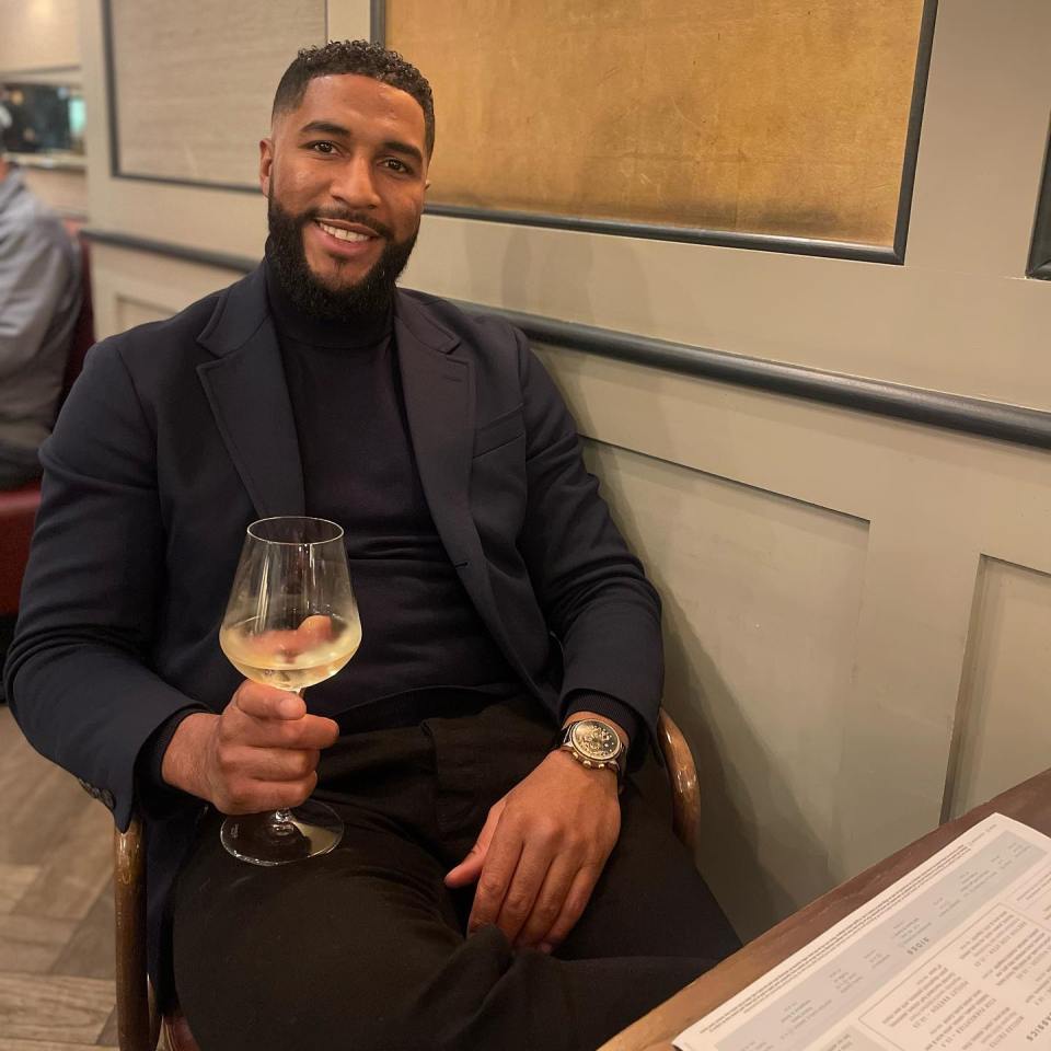 a man in a suit is holding a glass of wine