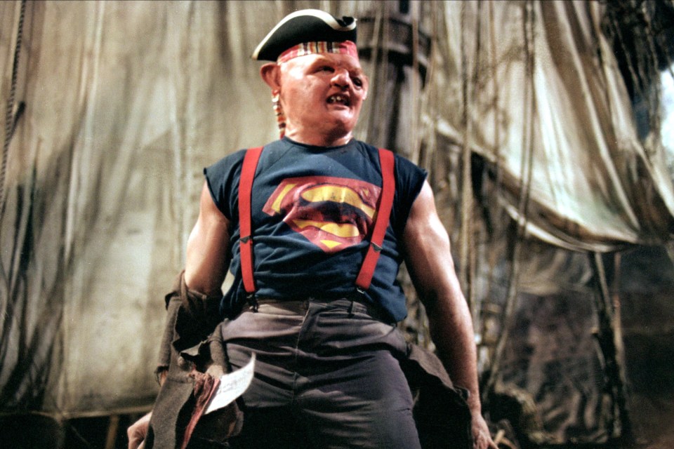 a man wearing a superman shirt and suspenders