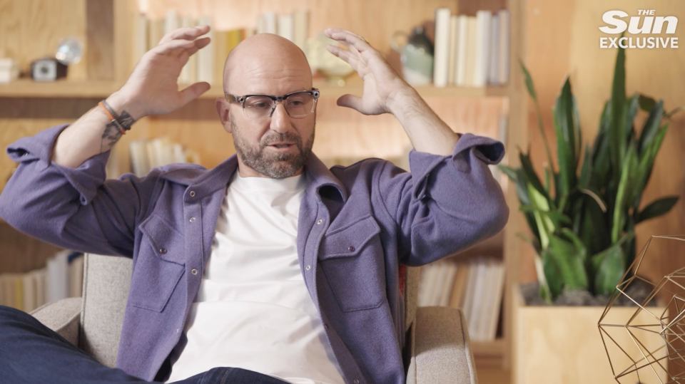 a man wearing glasses and a purple shirt is sitting in front of a sun exclusive