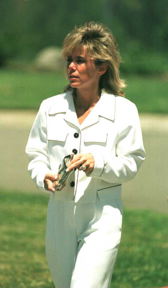 a woman in a white suit is holding a purse