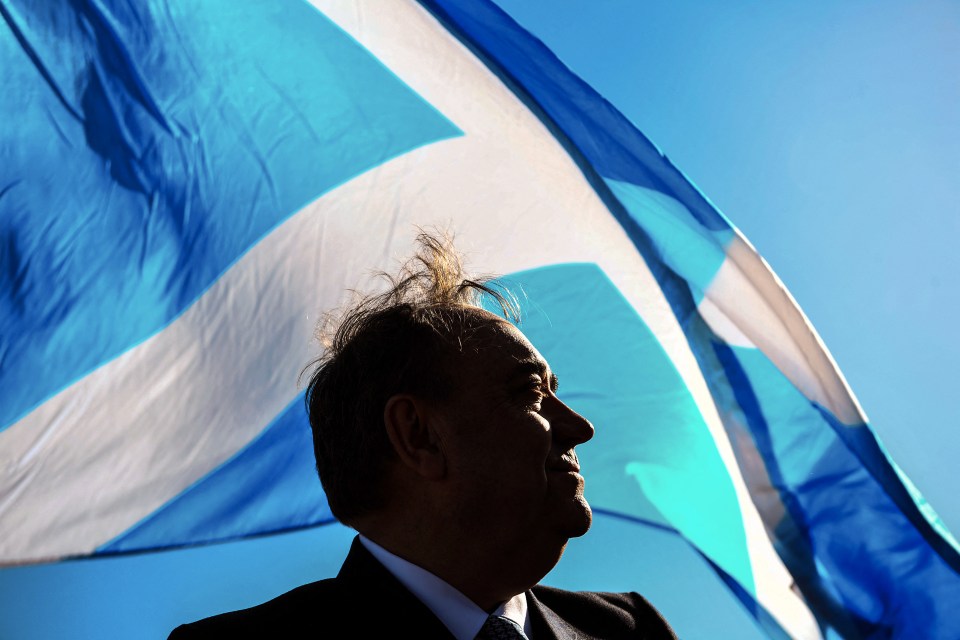 a man stands in front of a blue and white flag