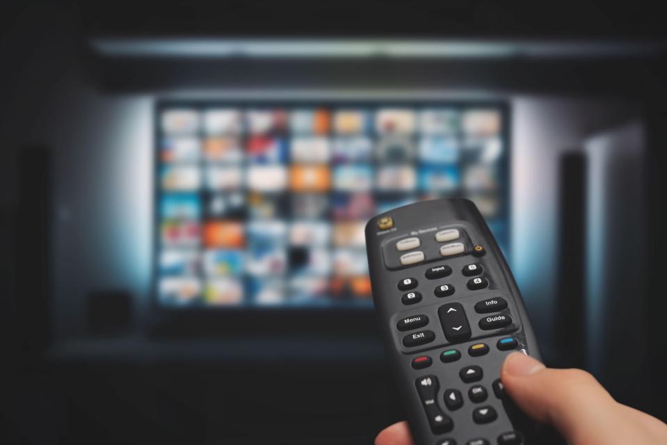 a person is holding a remote control in front of a television