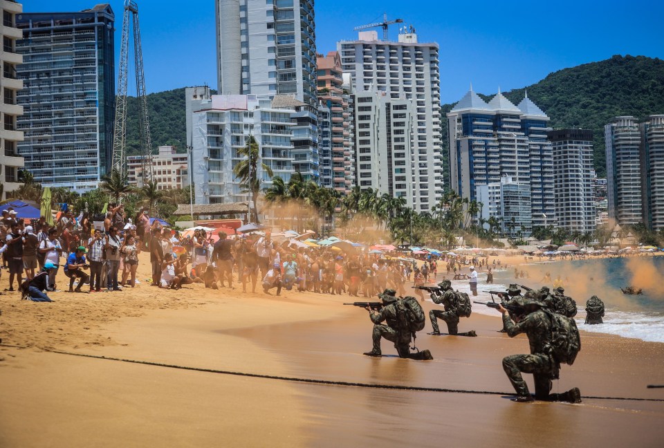 a group of soldiers are kneeling on a beach in front of a crowd