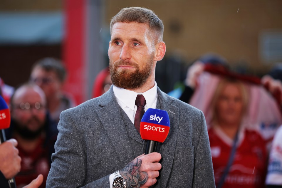 a man in a suit is holding a microphone that says sky sports